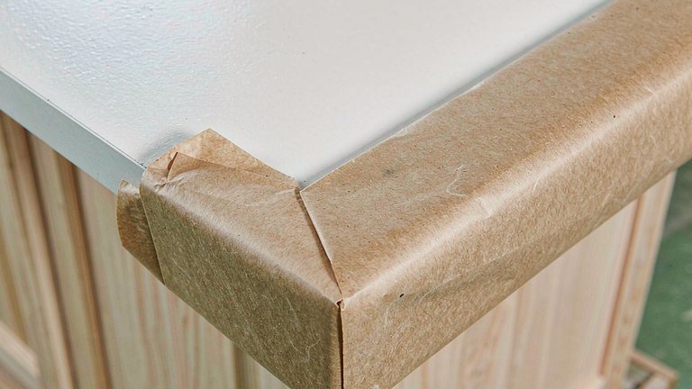 Paper corner protector fitted to a finished furniture panel